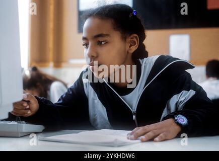 Ragazza afroamericana nera in uniforme scolastica in classe scolastica al suo computer di scrivania, studentessa africana nera 9-11 anni in classe studiando al suo terminale di computer Foto Stock