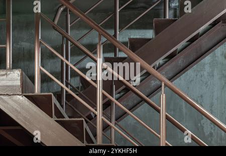 Vista laterale dei predellini in metallo vecchio con corrimano sullo sfondo della parete in cemento. Vista verticale della scala in acciaio, spazio per testo, messa a fuoco selettiva. Foto Stock