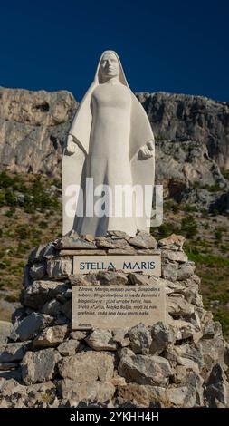 Statua della Vergine Maria sulle montagne croate, con una targa di preghiera "Ave Maria" circondata dalla natura. Foto Stock