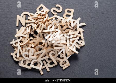Potete vedere nell'immagine le lettere di legno su uno sfondo della lavagna, disposte in modo casuale Foto Stock