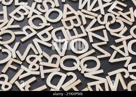 Potete vedere nell'immagine le lettere di legno su uno sfondo della lavagna, disposte in modo casuale Foto Stock