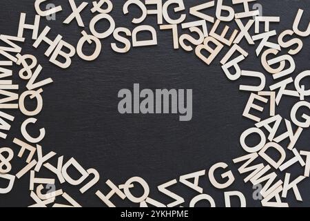 Potete vedere nell'immagine le lettere di legno su uno sfondo della lavagna, disposte in modo casuale Foto Stock