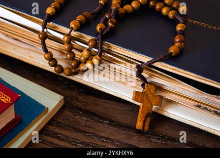 Perline di rosario in legno su vecchi libri. Sfondo in legno. Foto Stock