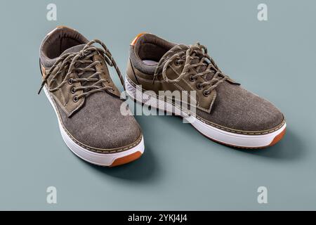 Scarpe in tela cachi su sfondo blu argento. Un paio di nuove sneaker marroni con suola bianca per il fitness e lo stile di vita attivo. Scarpe sportive casual. Foto Stock