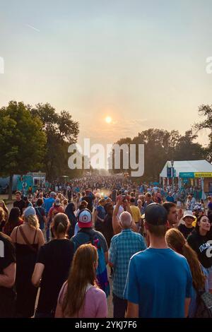 Folle di persone sotto il tramonto rosso in una fiera statale Foto Stock