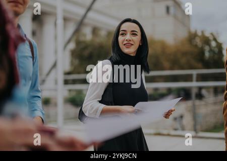 Donna d'affari sicura che cammina con i colleghi per le strade della città Foto Stock