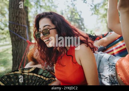 Giovane donna che ride e si rilassa con gli amici in un'amaca all'aperto in una giornata di sole Foto Stock