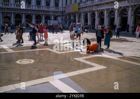 I turisti documentano l'aumento della marea raggiungendo Piazza San Marco a Venezia, Italia Foto Stock