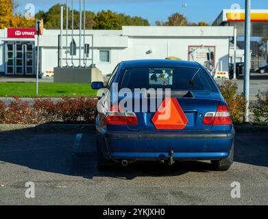 Un trattore a blu è parcheggiato in molto, con un triangolo arancione luminoso sul retro. La scena si svolge in una limpida giornata autunnale con colorfu Foto Stock