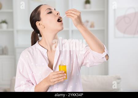 Giovane donna che prende tintura CBD all'interno. Estratto di erbe Foto Stock