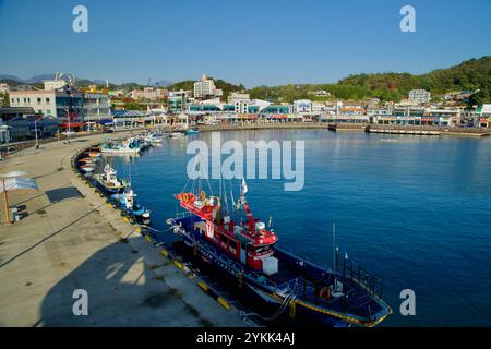 Sokcho, Corea del Sud - 3 novembre 2024: Barche da pesca ormeggiate lungo il vivace lungomare del porto di Daepo, circondate da ristoranti e negozi di pesce, cr Foto Stock