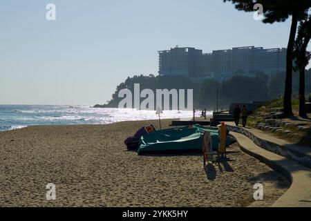 Sokcho, Corea del Sud - 3 novembre 2024: Una serena vista della spiaggia di Sokcho durante il tramonto, con le onde scintillanti nella luce e il Lotte Resort arroccato Foto Stock