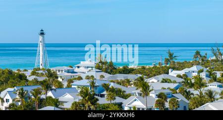 Ville costose tra palme verdi nella piccola cittadina dell'isola di Boca grande, nel sud-ovest della Florida, Stati Uniti. Faro bianco sulla riva del mare per uso commerciale Foto Stock