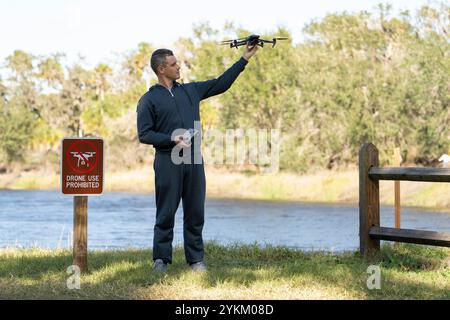 L'uomo volerà il suo quadricottero in nessuna zona di droni. L'operatore utilizza illegalmente il proprio UAS nel parco statale vicino al segnale di restrizione Foto Stock