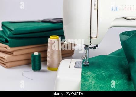 Macchina da cucire in azione con tessuto e fili sul tavolo da lavoro per realizzare progetti Foto Stock