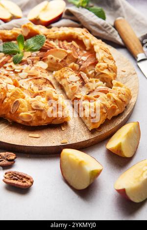 galette di mele appena sfornata, decorata con scaglie di mandorle e foglie di menta, servita su una tavola di legno Foto Stock