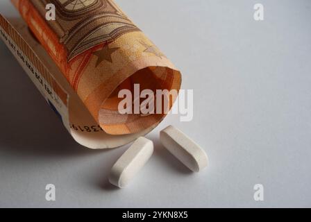 Un'immagine concettuale della crescente spesa della medicina, con pillole sulla valuta. Foto Stock