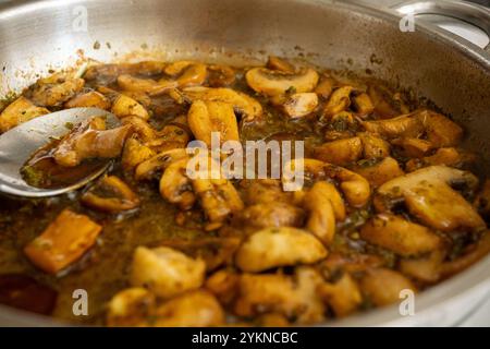 Primo piano di funghi saltati che cucinano in una padella con salsa di soia per un piatto saporito Foto Stock