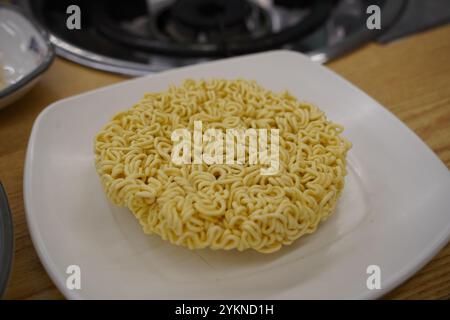 Spaghetti istantanei in un piatto bianco su un tavolo di legno Foto Stock