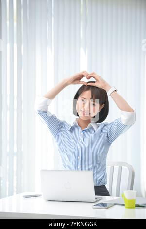 Lavoratrice che fa un segno di cuore con le mani Foto Stock