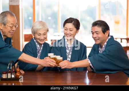 Una coppia di mezza età in yukata e haori che brinda con birra e i nonni Foto Stock