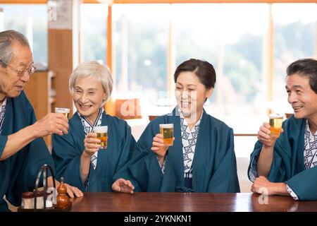 Una coppia di mezza età in yukata e haori che brinda con birra e i nonni Foto Stock