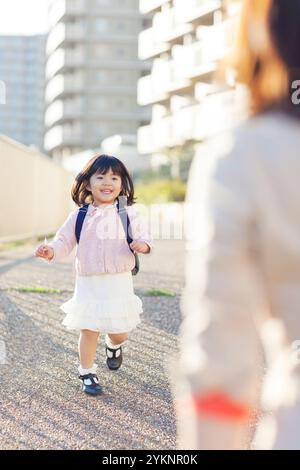 Ragazza dell'asilo che corre verso la madre Foto Stock