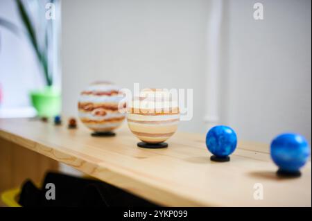 Sistema solare Montessori su ripiano in legno. Sfere planetarie dipinte che rappresentano pianeti, disposte in dimensioni e gradiente di colore in un asilo Foto Stock