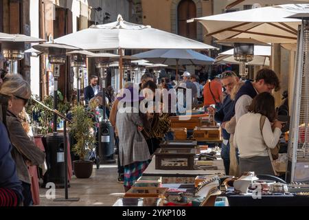 Arezzo, Italia - 2 novembre 2024: I visitatori curiosano tra i pezzi d'antiquariato del mercato mensile del centro storico di Arezzo, esplorando gli oggetti esposti dai venditori lungo le strade e le piazze Foto Stock