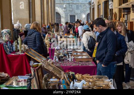 Arezzo, Italia - 2 novembre 2024: I visitatori curiosano tra i pezzi d'antiquariato del mercato mensile del centro storico di Arezzo, esplorando gli oggetti esposti dai venditori lungo le strade e le piazze Foto Stock