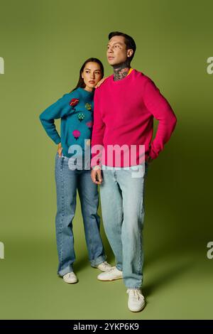 Una giovane coppia elegante sfoggia i propri outfit con espressioni giocose in colori brillanti. Foto Stock