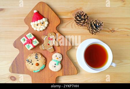 Biscotti di Natale assortiti con una tazza di tè caldo servito su un tavolo di legno Foto Stock