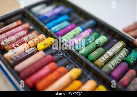 Una scatola di colori pastello ad olio in varie tonalità, alcune usate e macchiate, disposte in un vassoio di plastica Perfetto per attività artistiche e creative Foto Stock