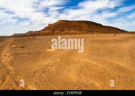 Deserto di pietra secca e montagna solitaria sullo sfondo. Marocco Foto Stock