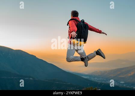 Un uomo felice viaggiatore con braccia allungate che saltano in aria sulla cima della montagna. Viaggi avventurosi. concetto di successo libertà libera. Foto Stock