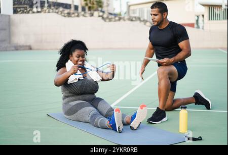 Donna curvy africana e personal trainer che fa una sessione di allenamento fitness all'aperto - attività Fit e concetto di stile di vita sano - Focus principale sul viso della ragazza Foto Stock