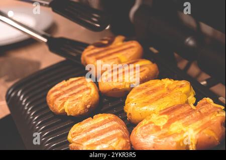 Verdure alla griglia. Il processo di cottura delle patate ruvide su un grill elettrico Foto Stock