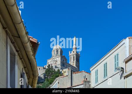 la basilica di Notre-Dame de la Garde a Marsiglia, con la sua statua dorata e l'architettura suggestiva, si staglia su un cielo azzurro e limpido, attirando molte persone Foto Stock