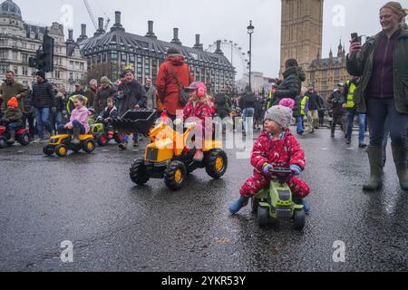 Londra, Regno Unito. 19 novembre 2024 i bambini viaggiano su trattori giocattolo in Parliament Square durante una manifestazione degli agricoltori mentre migliaia di agricoltori sono scesi a Whitehall per protestare contro i cambiamenti alla tassa di successione annunciati dal cancelliere Rachel Reeves nel bilancio del mese scorso. Gli agricoltori affermano che sarà sempre più difficile passare le aziende attraverso generazioni a causa di costi fiscali aggiuntivi. Credito. Amer Ghazzal/Alamy Live News Foto Stock