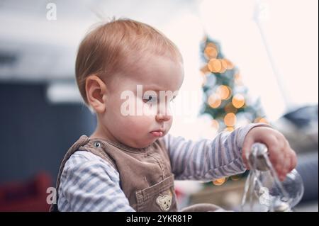 Bambino piccolo impegnato in attività ludiche mentre esplora le decorazioni per le vacanze a casa Foto Stock