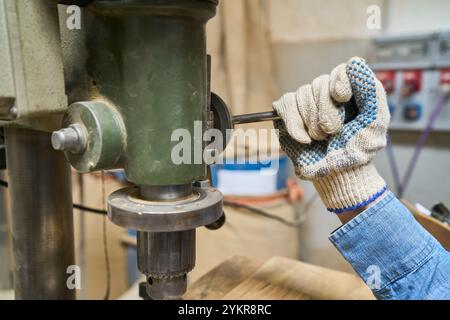 Primo piano di un macchinario con guanti in legno. L'immagine evidenzia le misure di precisione e sicurezza nell'ambiente di lavoro industriale Foto Stock