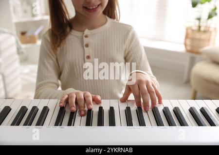 Ragazza che gioca al sintetizzatore al chiuso, primo piano. Strumento musicale elettronico Foto Stock