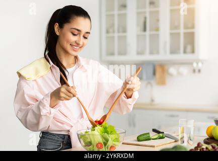 Ritratto di giovane donna sorridente che cucinava insalata fresca Foto Stock