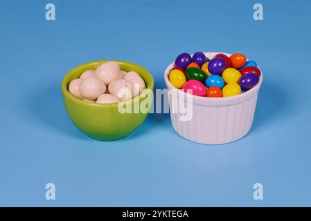 Palle di gomma da masticare di diversi colori in contenitori lucidi in terracotta con uno sfondo colorato omogeneo per il posizionamento del testo Foto Stock