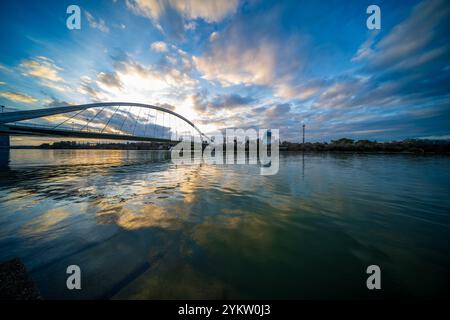 Ponte Barqueta che si riflette sull'acqua del fiume all'isola di Cartuja durante il tramonto a Siviglia. Foto Stock