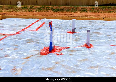I lavoratori si preparano per i lavori di fondazione posando tubi in plastica in cantiere Foto Stock