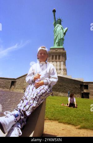 New York, USA, circa 1992. Ragazzo che posa di fronte alla Statua della libertà. Foto Stock