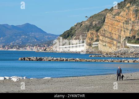 Sestri Levante, Italia - 14 novembre 2024. Spiaggia mediterranea in autunno. Persona vicino al mare con cane. Natura del mare e delle montagne. Setri Levante, Liguria. Foto Stock
