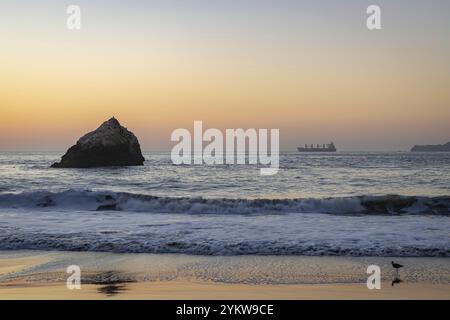 Una foto del sole che tramonta sullo stretto del Golden Gate e Baker Beach, con una nave cargo all'estrema destra Foto Stock