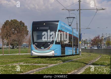 Un'immagine di un tram blu a Smirne su sentieri con erba verde Foto Stock